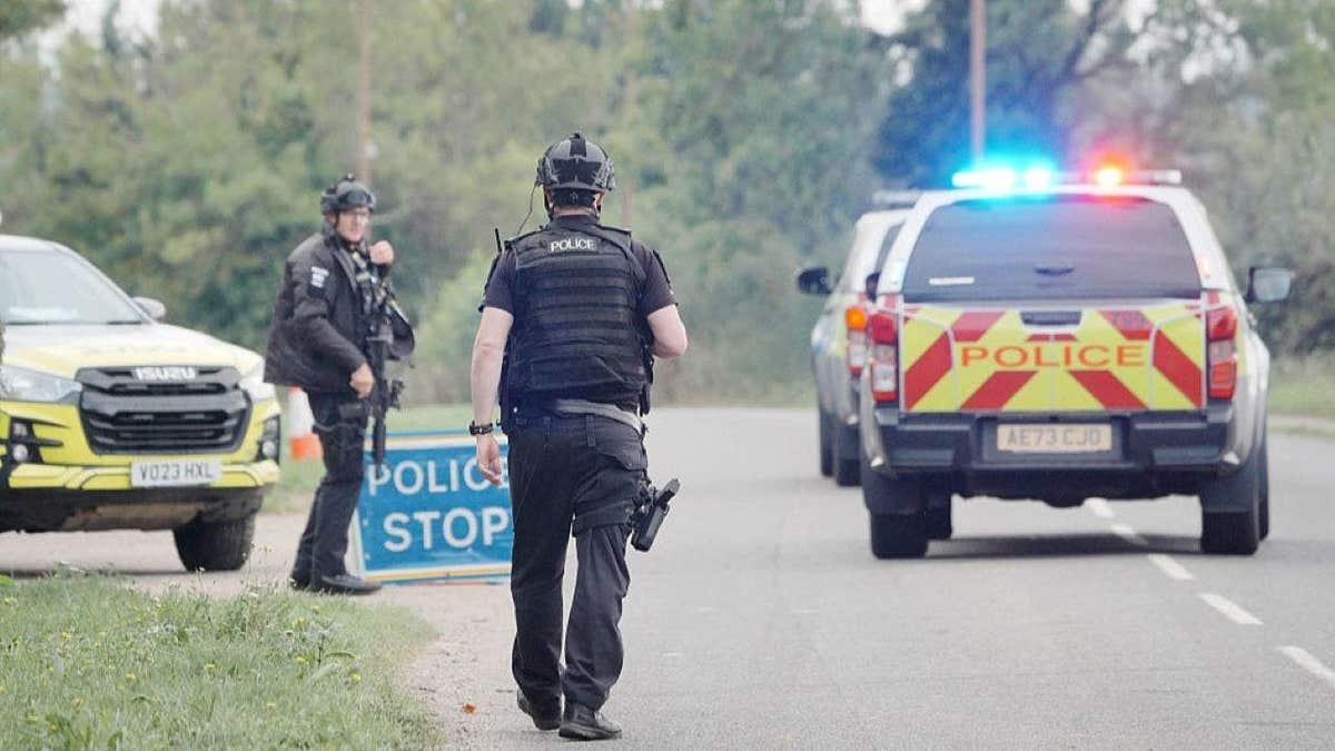 Armed officers and marked police vehicles holding a road near RAF Fairford